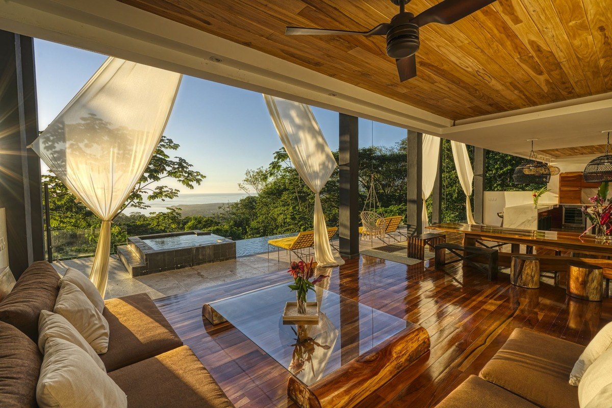 Kitchen has island with seating, ocean view, and woven light fixtures.