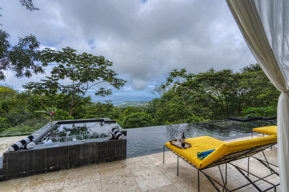 Infinity pool and hot tub overlook rainforest and ocean.