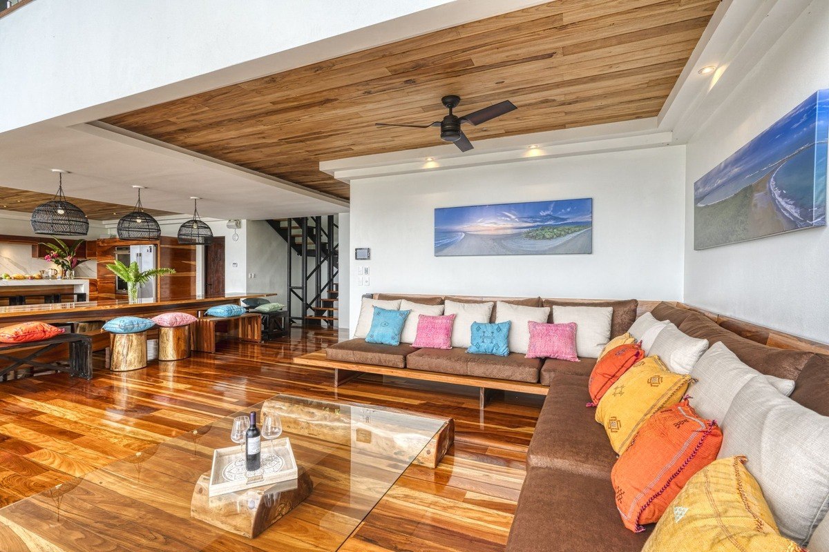 Living room has large sectional sofa, wood floors, and wood ceiling.