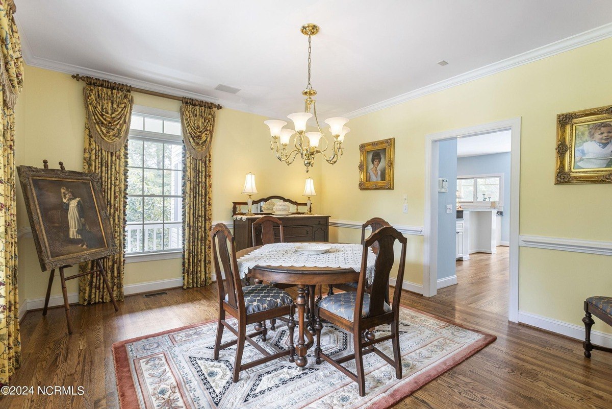 Dining room has hardwood floors, a wood table and chairs, and yellow walls.