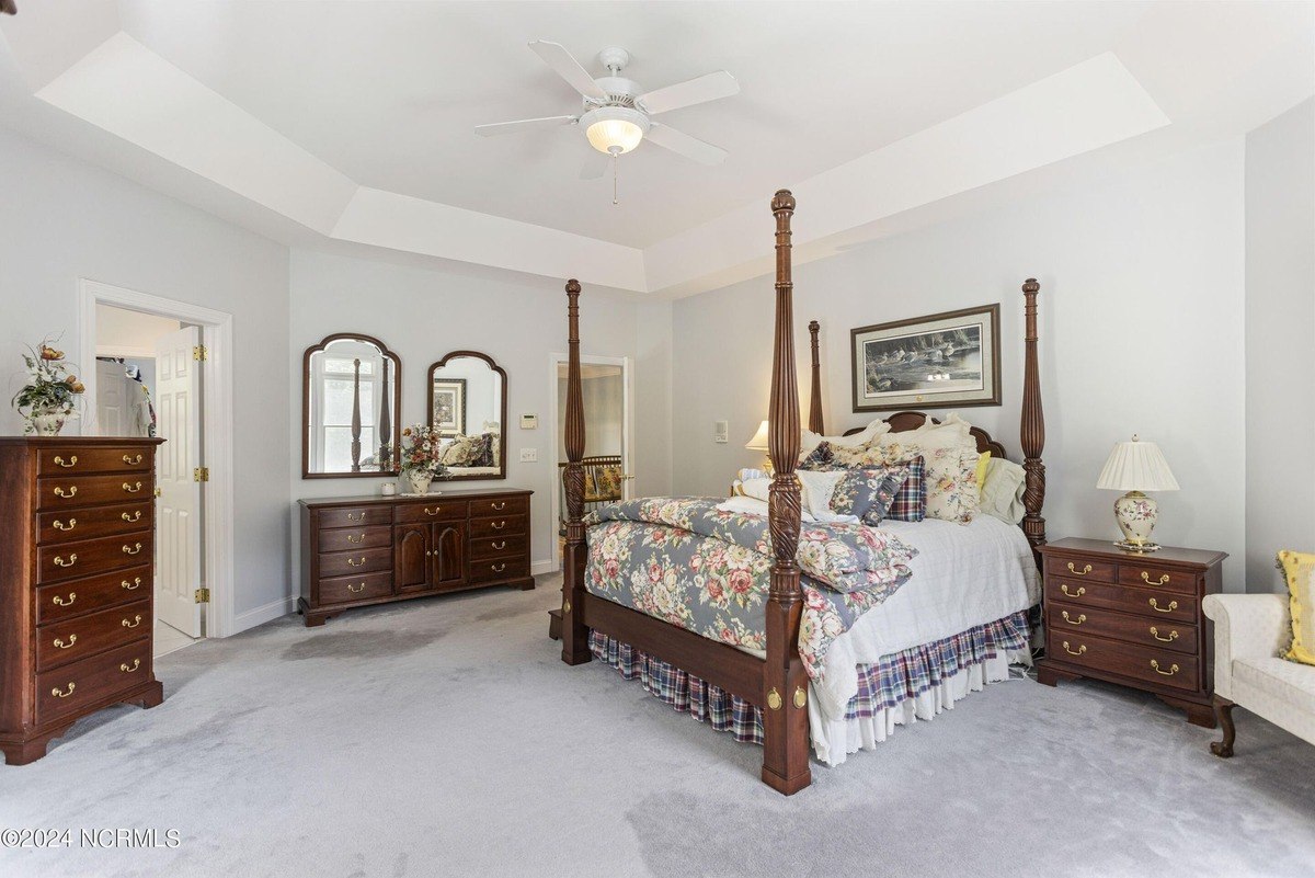 Master bedroom has carpeted floors, a four-poster bed, and matching wood furniture.