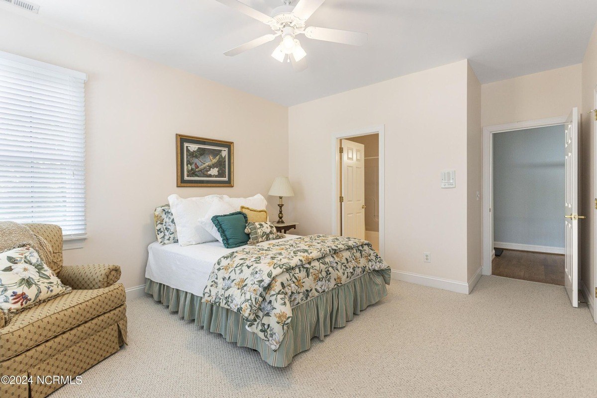 Bedroom has carpeted floors, a ceiling fan, and a floral comforter.