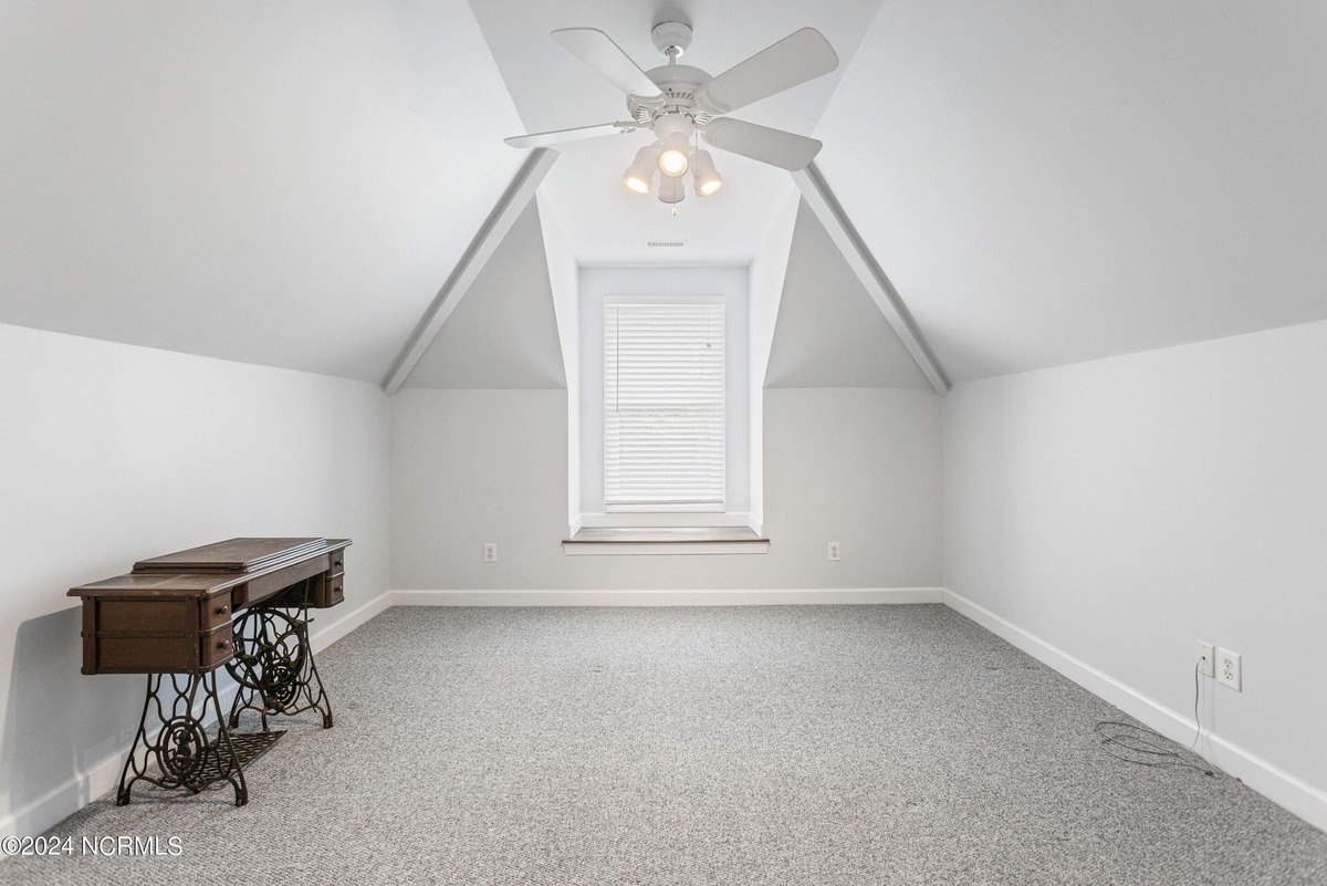 Room has gray carpeting, a ceiling fan, and a window with blinds.