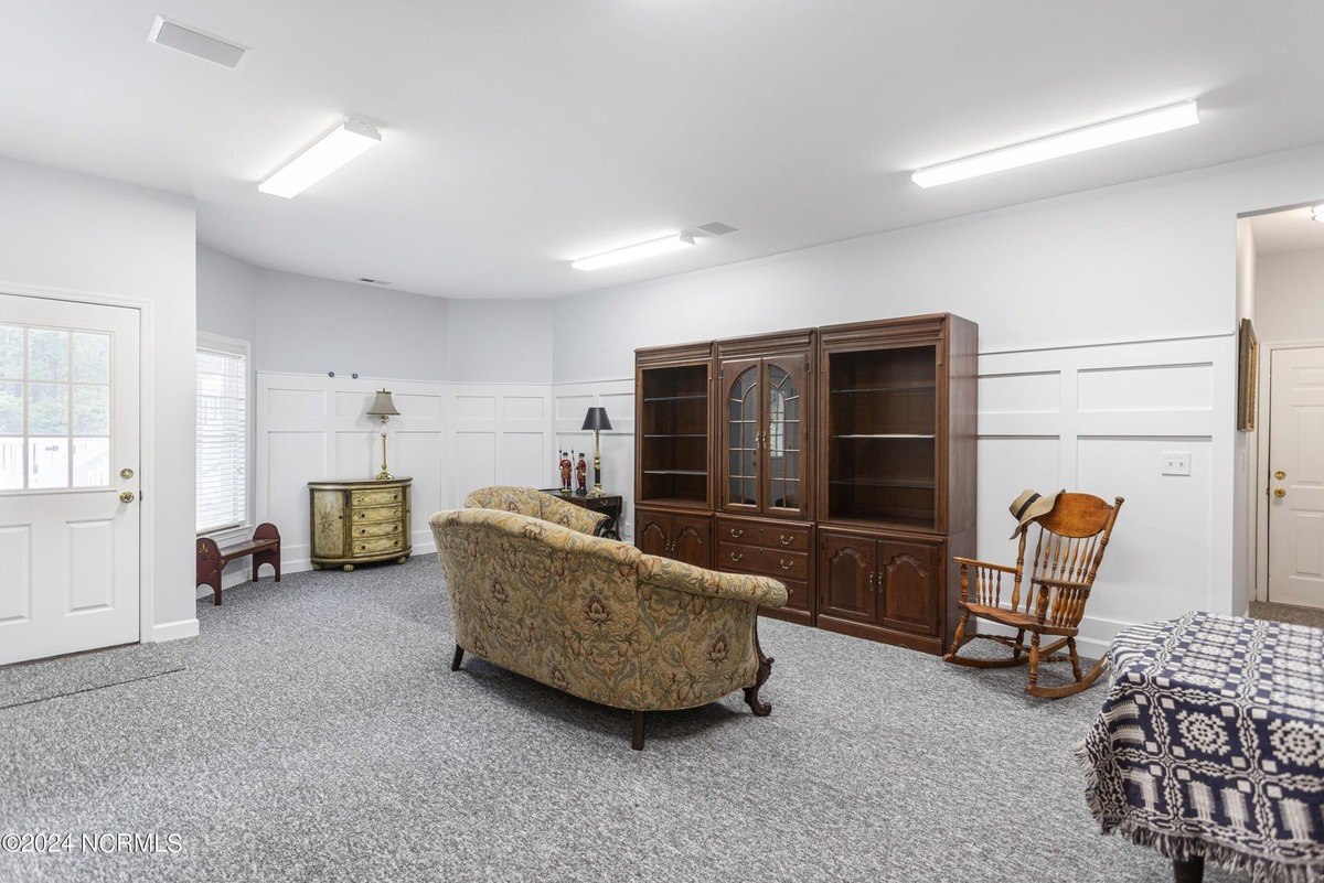 Room has gray carpeting, wood furniture, and white walls.