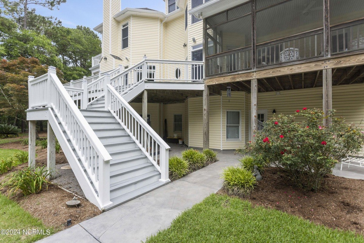 House has a large deck with stairs leading down to a patio.