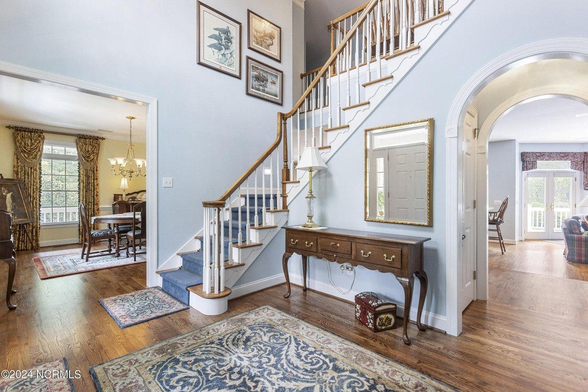 Entryway has hardwood floors, a staircase, and a console table with artwork on the wall.