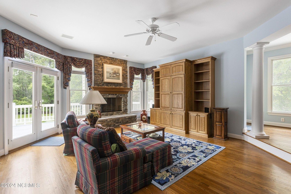 Living room has hardwood floors, a fireplace, built-in shelving, and a ceiling fan.