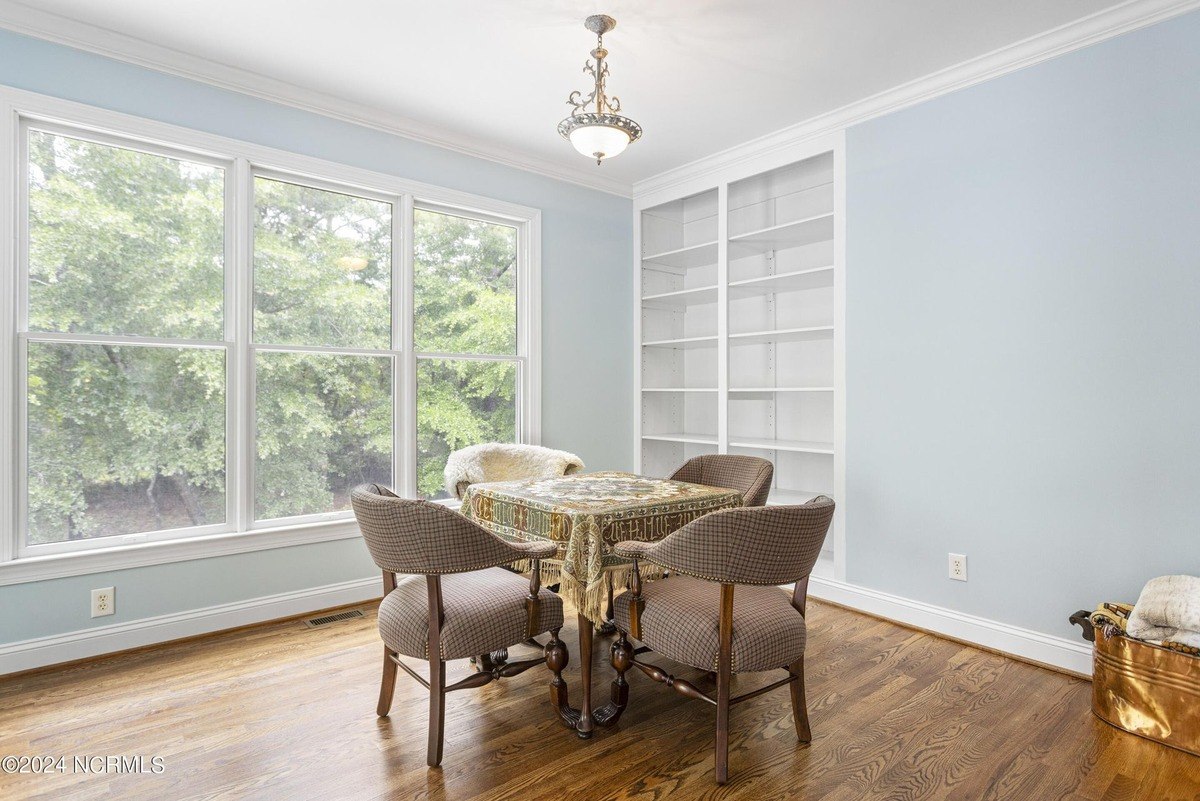 Room has hardwood floors, built-in shelving, and a small table with chairs.