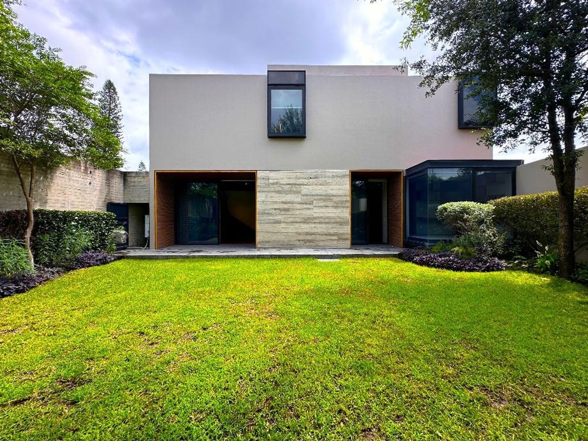 Backyard showcasing a minimalist structure with a lawn surrounded by landscaping.