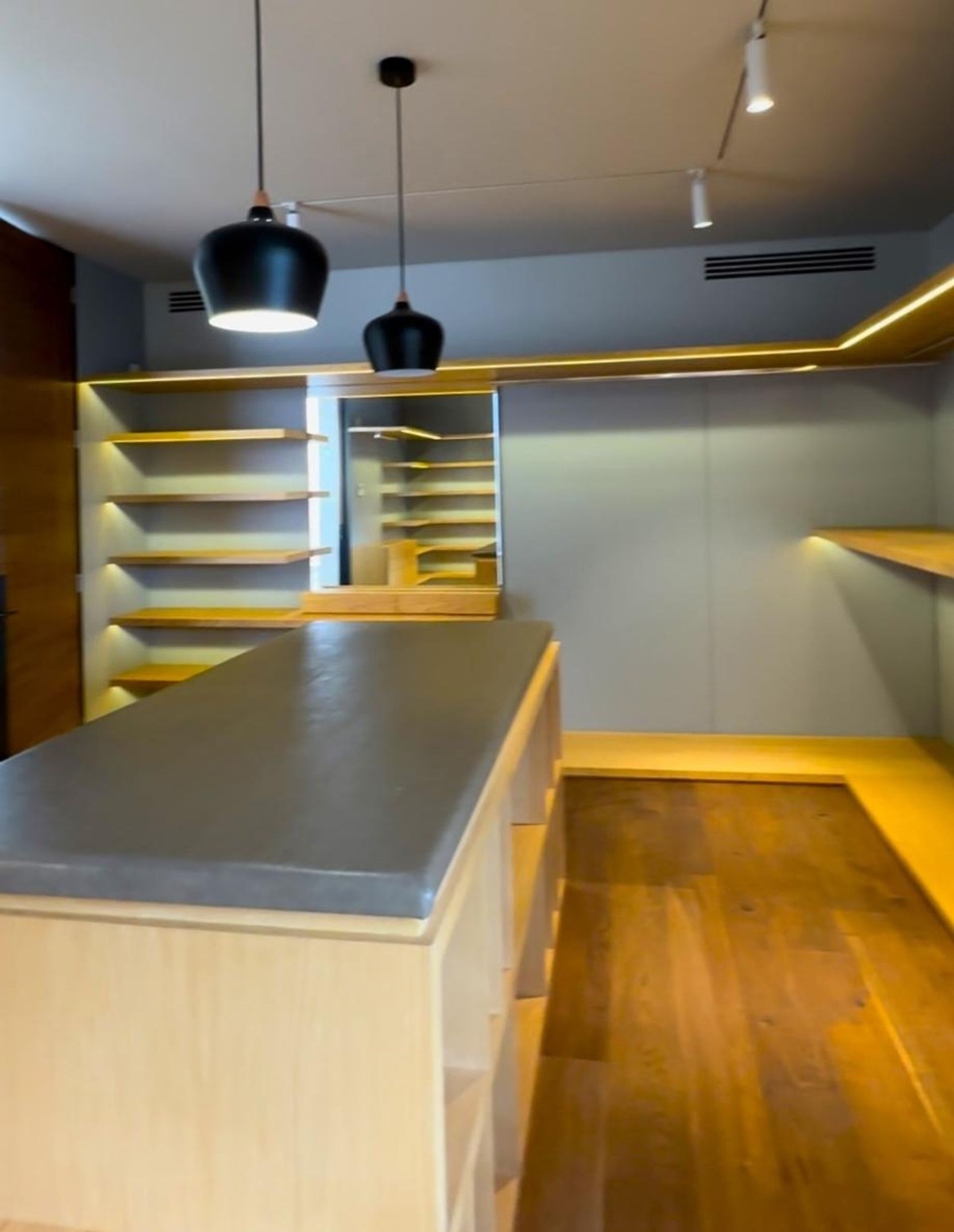 Spacious walk-in closet with wooden shelving and pendant lighting.