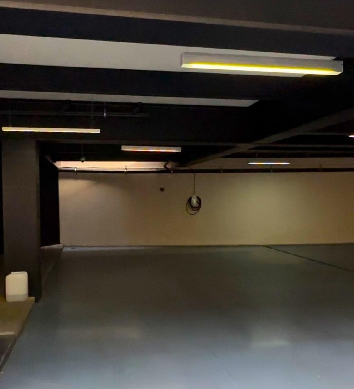 Indoor parking garage with a minimalist design and dark ceiling beams.