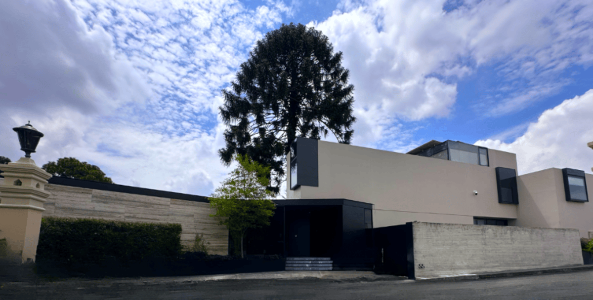 Modern exterior facade featuring beige walls, glass windows, and a tall tree.