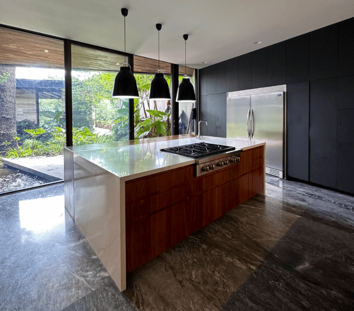 Alternate kitchen angle highlighting floor-to-ceiling glass windows overlooking a garden.