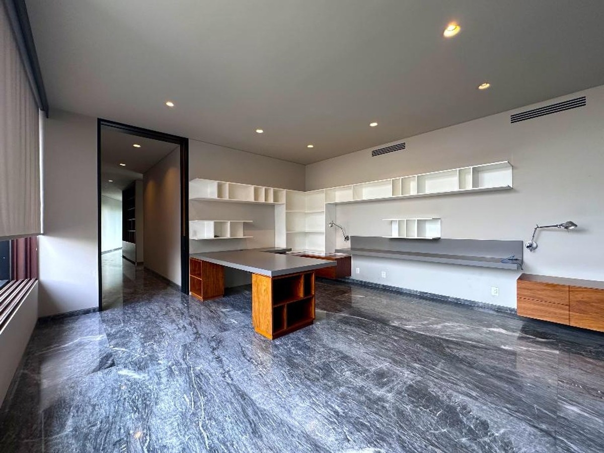 Spacious office with built-in shelving, a long desk, and sleek marble flooring.