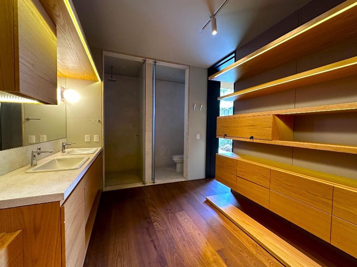 Bathroom with double sinks, wooden cabinetry, and a shower area with glass doors.