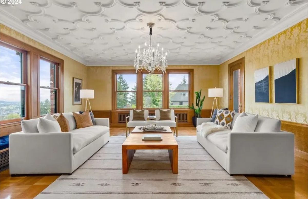 A formal living room featuring a detailed coffered ceiling and an ornate crystal chandelier.