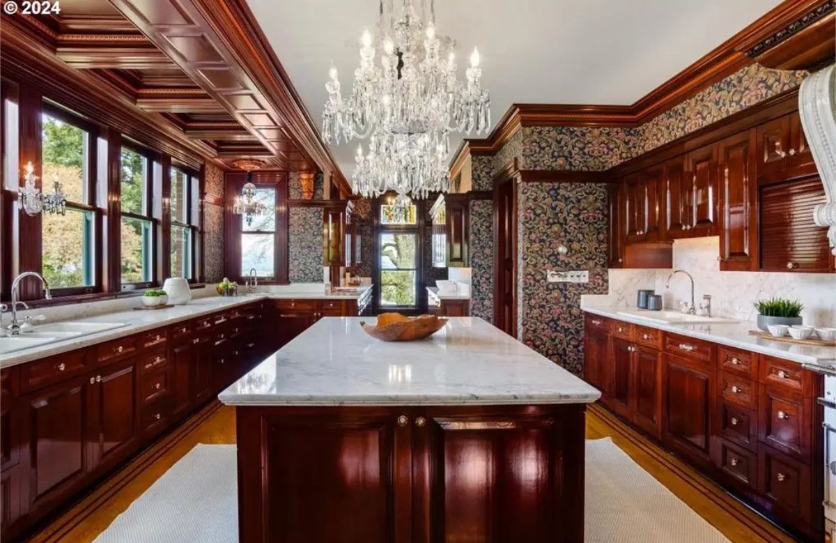 Dark wood cabinetry and coffered ceilings, marble countertops and a central island add a bright contrast to the dark tones, creating a refined look.