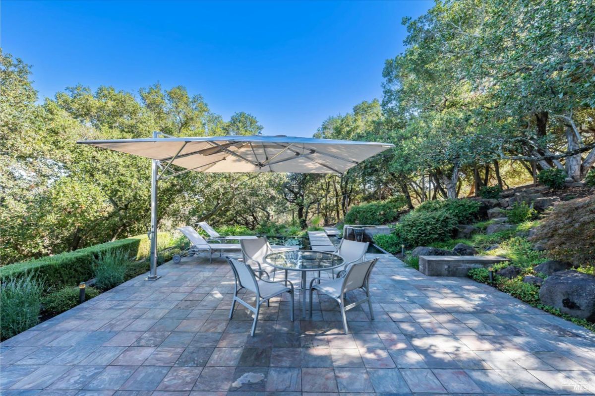 Outdoor patio with umbrella, table, chairs, and lounge chairs.