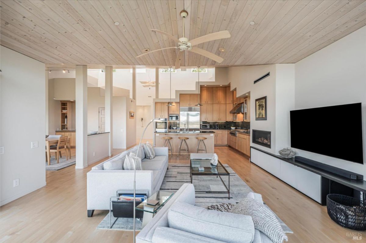 Open-concept living room connected to a kitchen and dining area with a modern design.