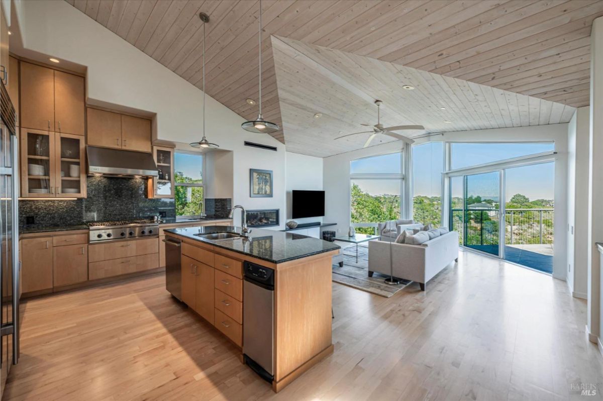 Open-plan kitchen and living area with wood finishes and large windows.