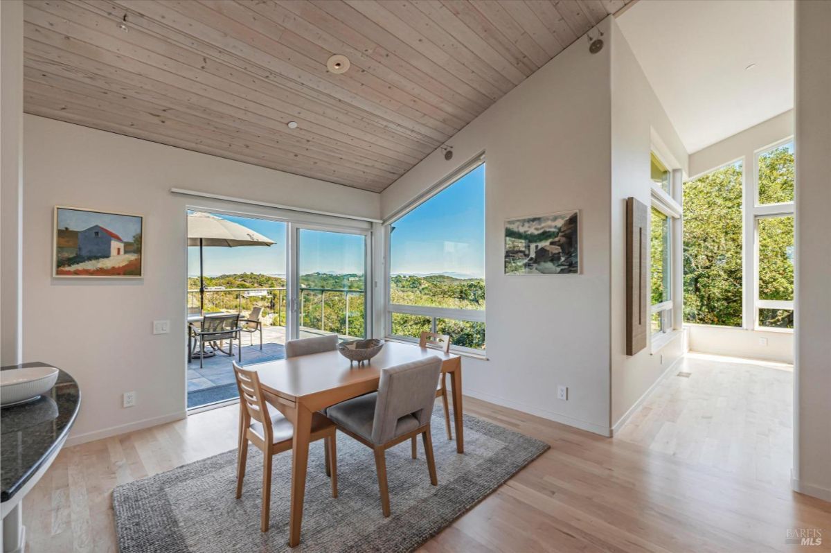 Dining area with large windows and access to an outdoor patio.