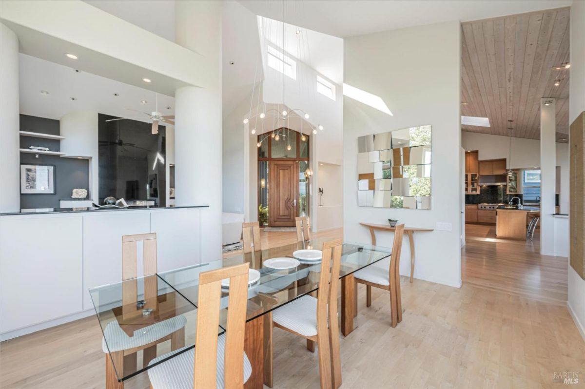 Glass dining table set in a high-ceiling room with modern decor.