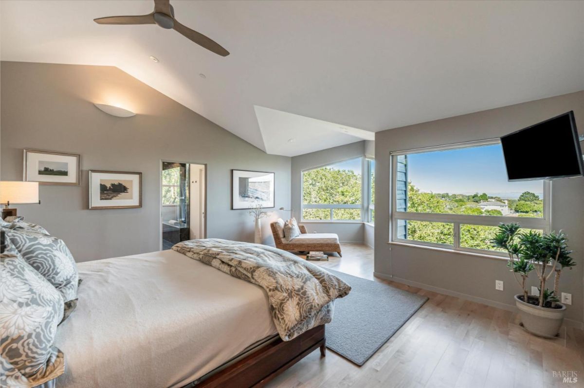 A different angle of the master bedroom showing additional windows and an adjacent bathroom entrance.