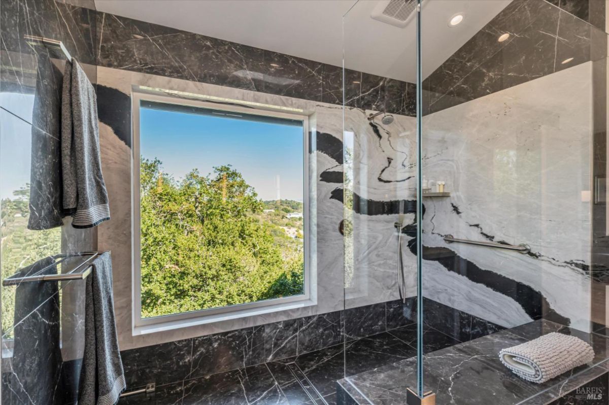 Ensuite bathroom with walk-in shower and window overlooking trees.