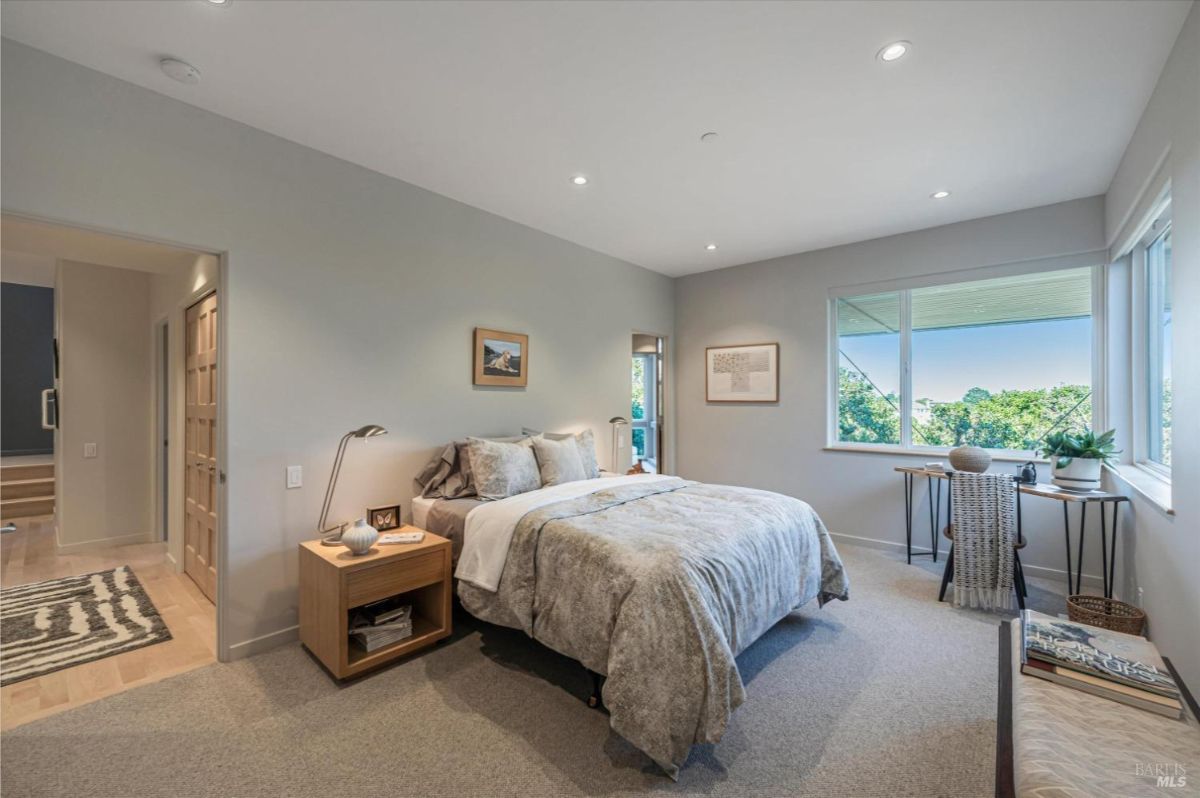 A second bedroom with a bed, a desk, and windows providing outdoor views.