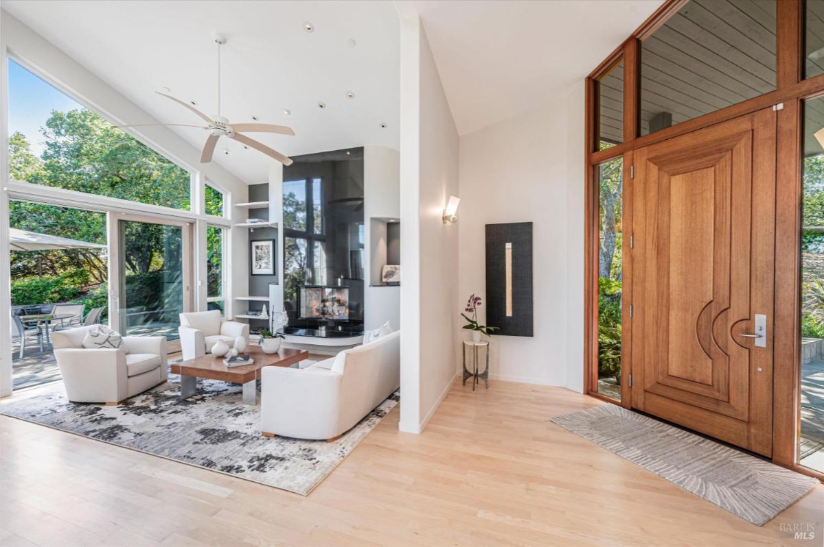 Living area with large windows, a ceiling fan, and sliding glass doors leading to a patio.