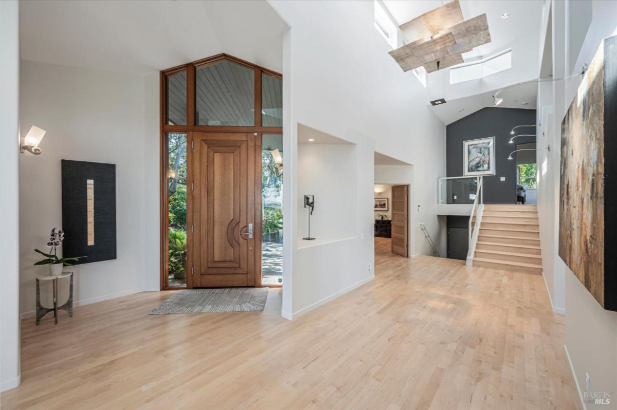 Bright and spacious foyer with wooden double doors and light wood flooring.