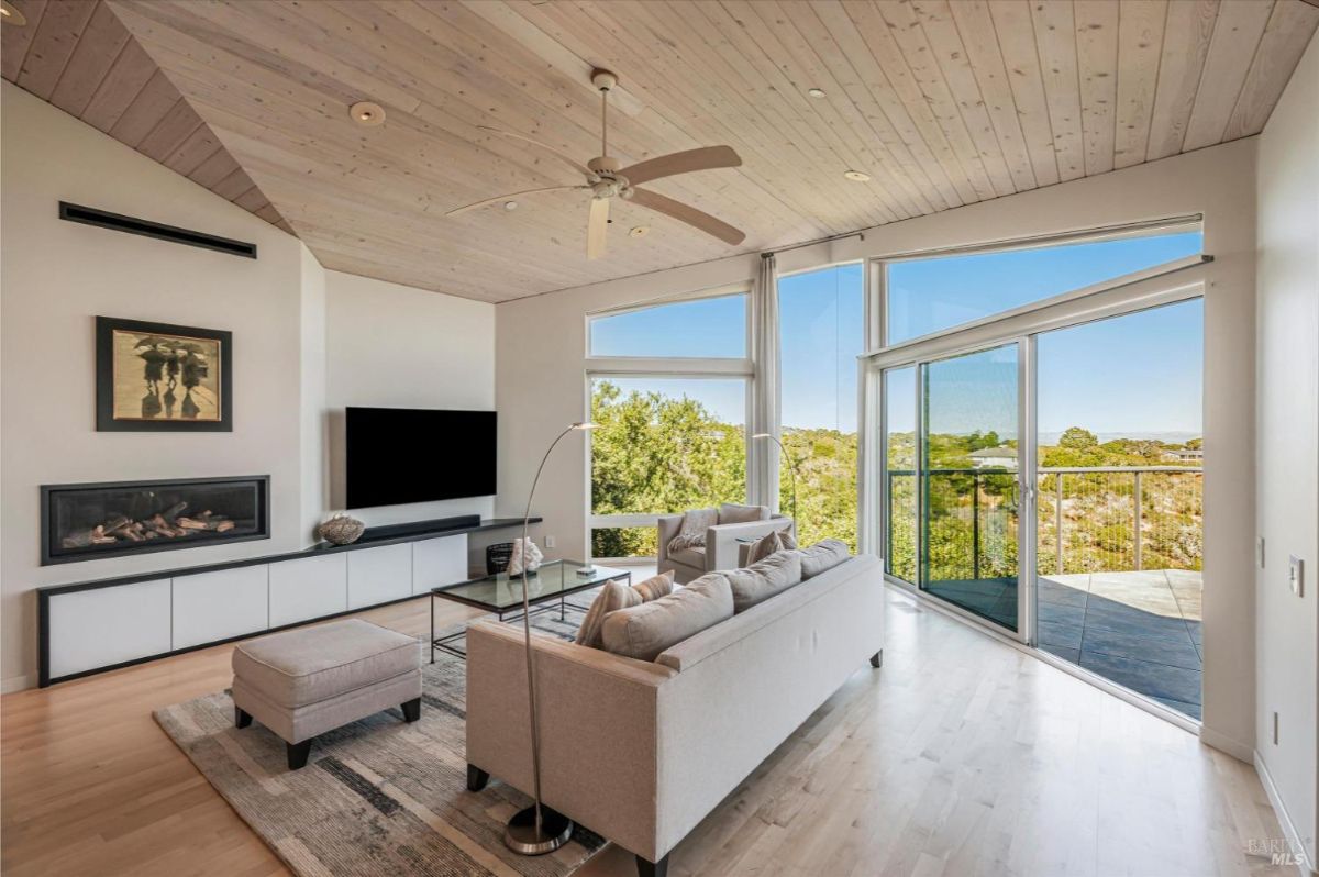 Cozy living area with views of a deck and surrounding hills through expansive windows.