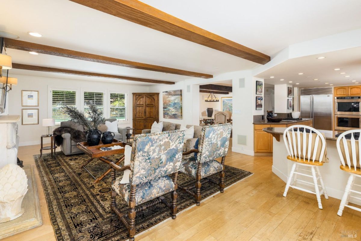 Open-plan living and dining area with floral patterned chairs and a kitchen bar with stools.