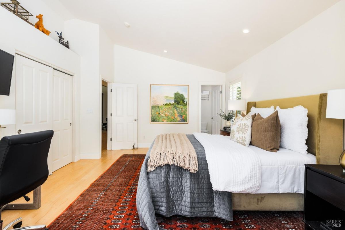 Bedroom featuring an angled ceiling, built-in closets, and a cozy sitting area with outdoor access.