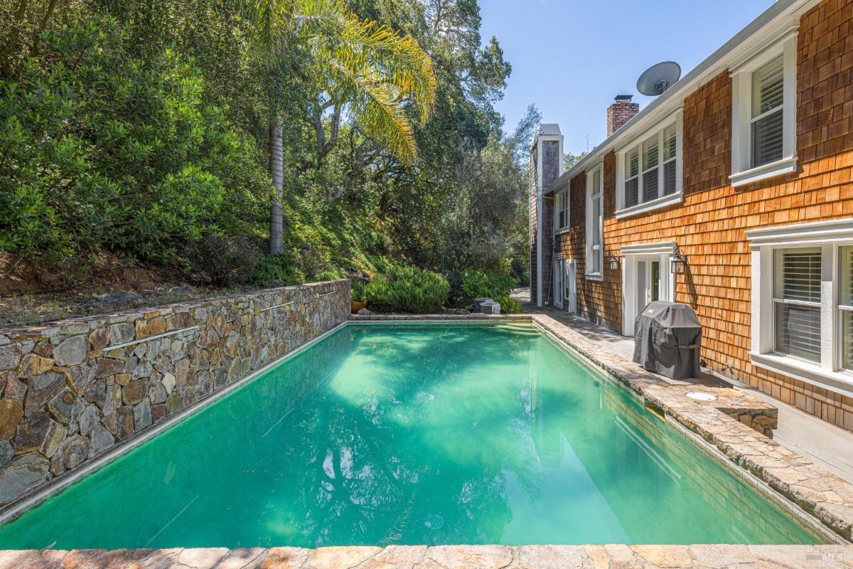 Backyard pool surrounded by stone walls and lush vegetation.