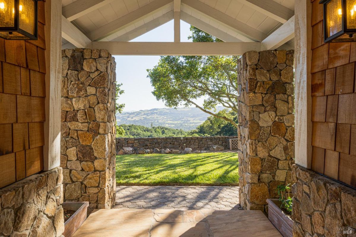 Stone archway with a view of the outdoor landscape and distant hills.