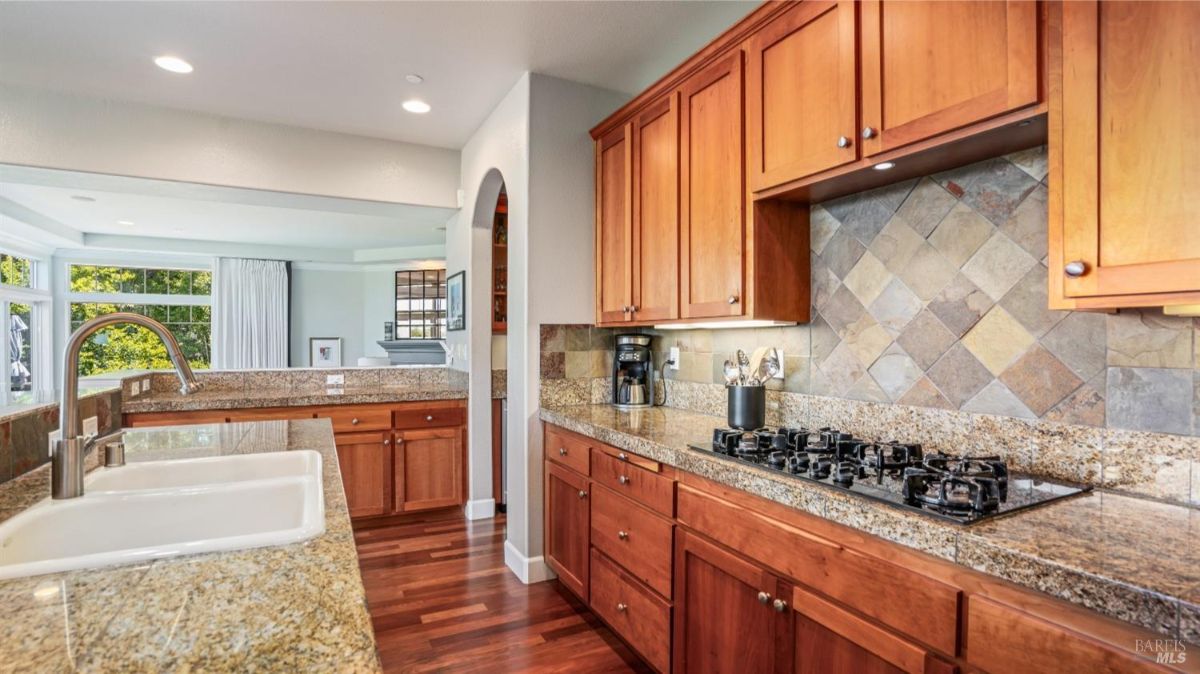 Kitchen with granite countertops, wooden cabinets, and a tiled backsplash featuring a gas stovetop.