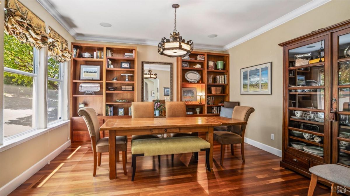 Dining room with built-in bookshelves, a wooden table, and upholstered chairs.