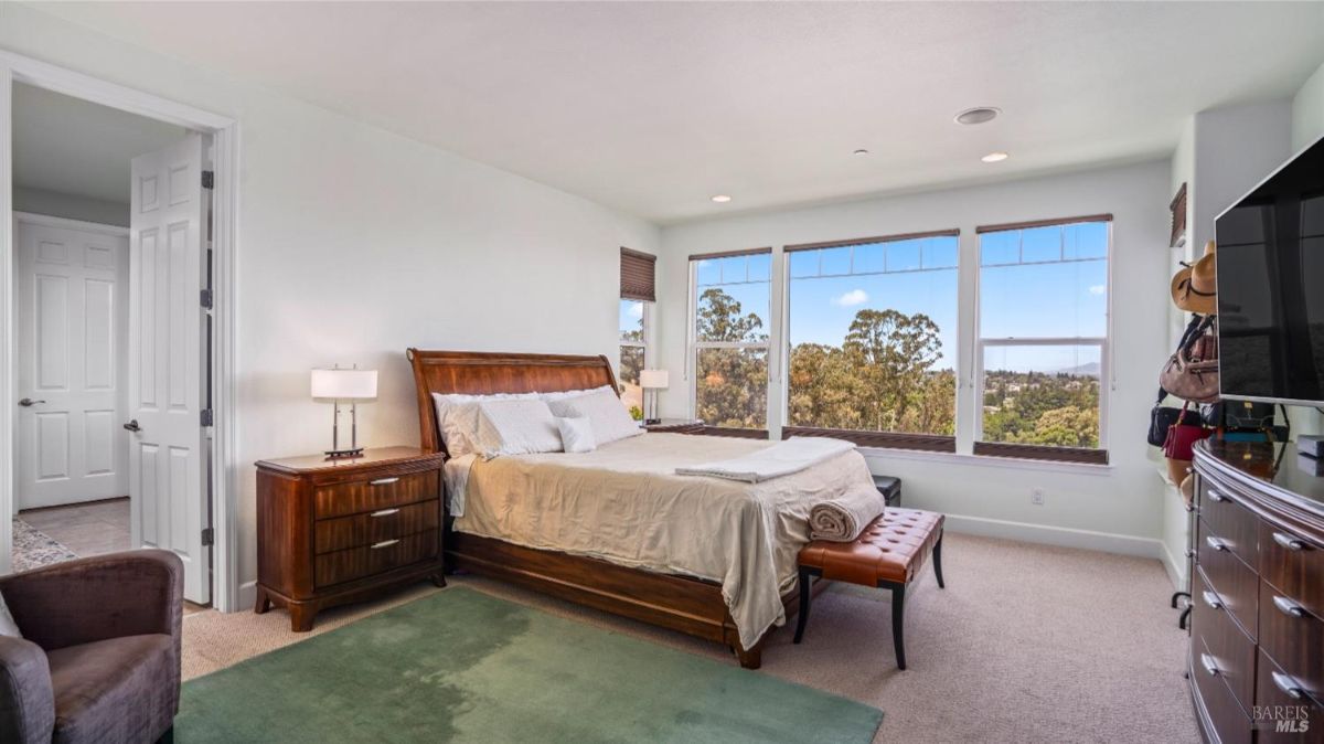 Bedroom with a large bed, wooden furniture, and windows offering scenic views.