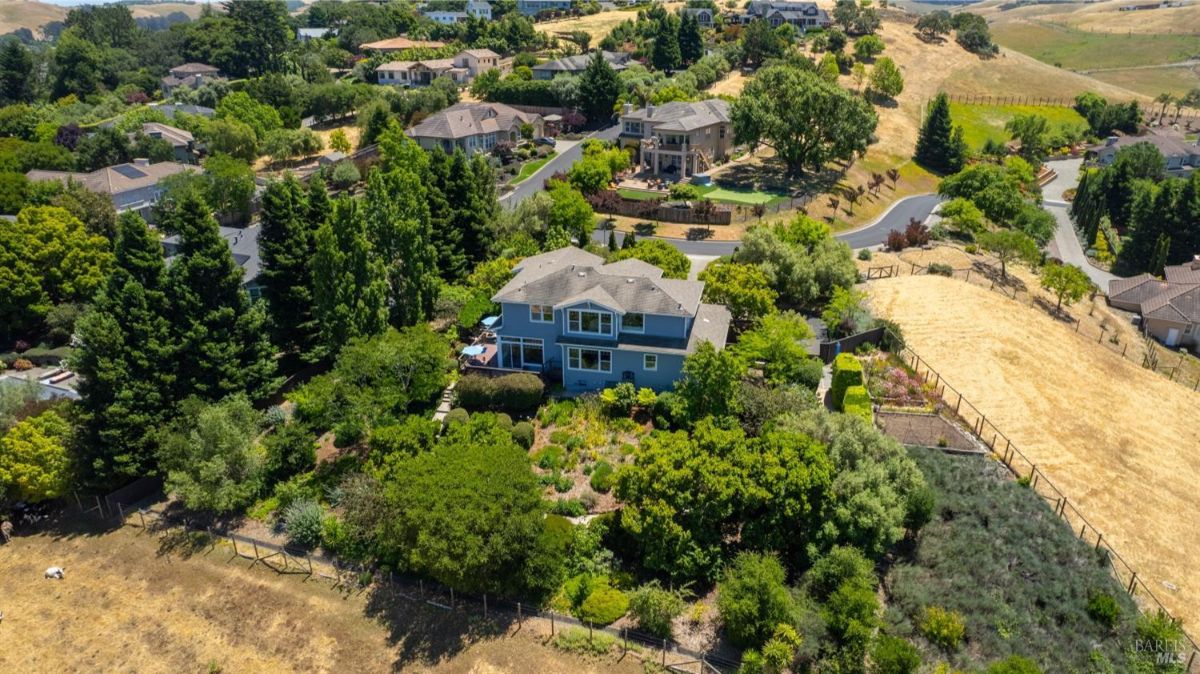 Two-story house nestled in lush landscaping with a mix of colorful trees and shrubs.