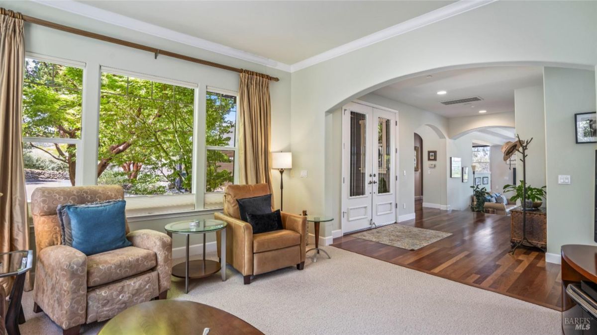 Sitting area near windows with natural light, featuring armchairs and a view of the entryway.