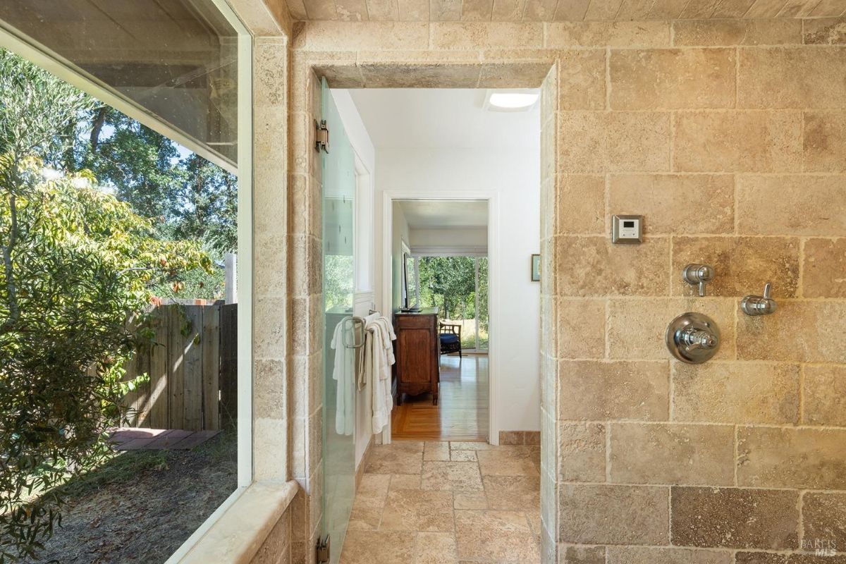 Stone-tiled shower with a large window and a view of the outdoors.