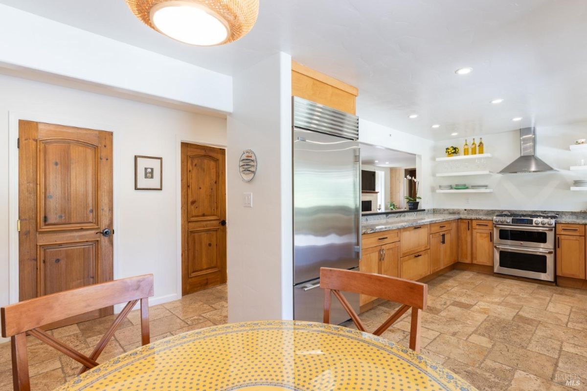 Kitchen and dining area with wooden doors, tiled flooring, and a stainless steel refrigerator.