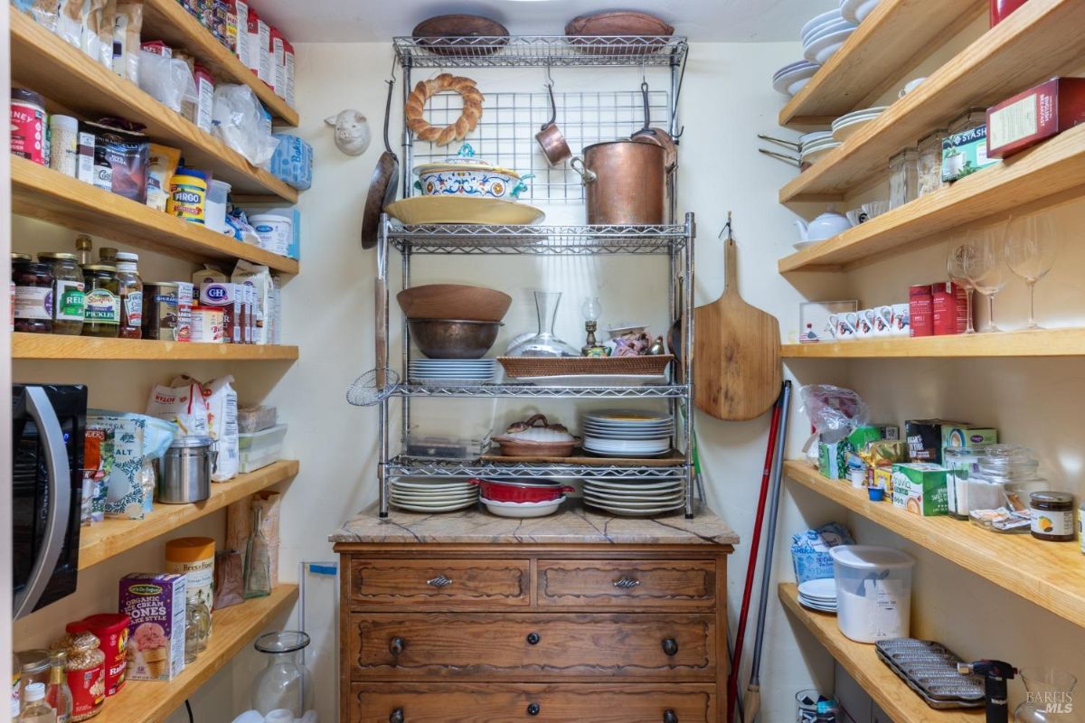 Pantry with wooden shelving, organized food items, and a vintage dresser.