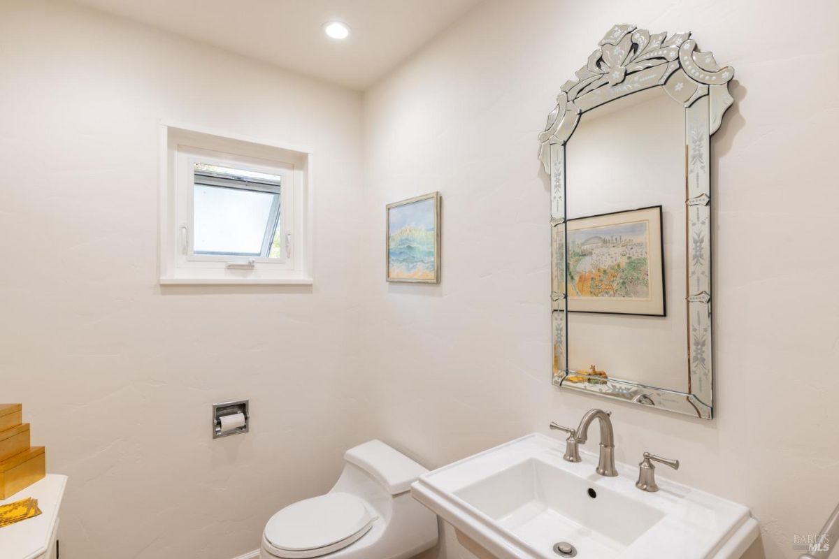 Small bathroom with white walls, a decorative mirror, and a compact sink.