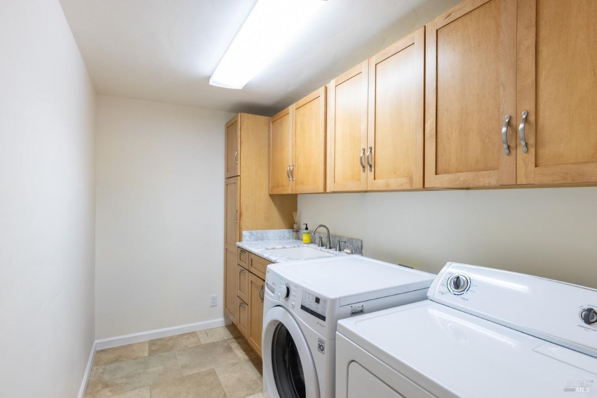 Laundry room with light wood cabinetry, tiled flooring, and a washer and dryer set.