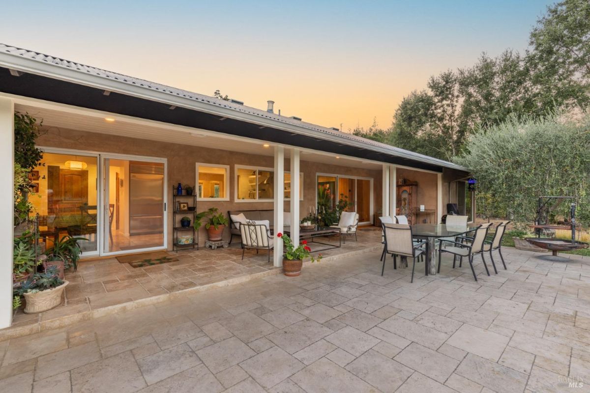 Backyard includes a tiled patio with dining furniture and large sliding doors leading to the house.