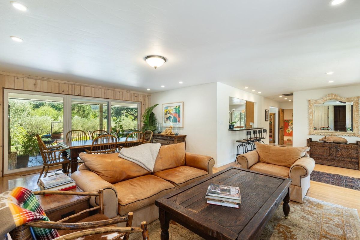 Living room with leather sofas, a wooden coffee table, and a view of the garden through sliding glass doors.