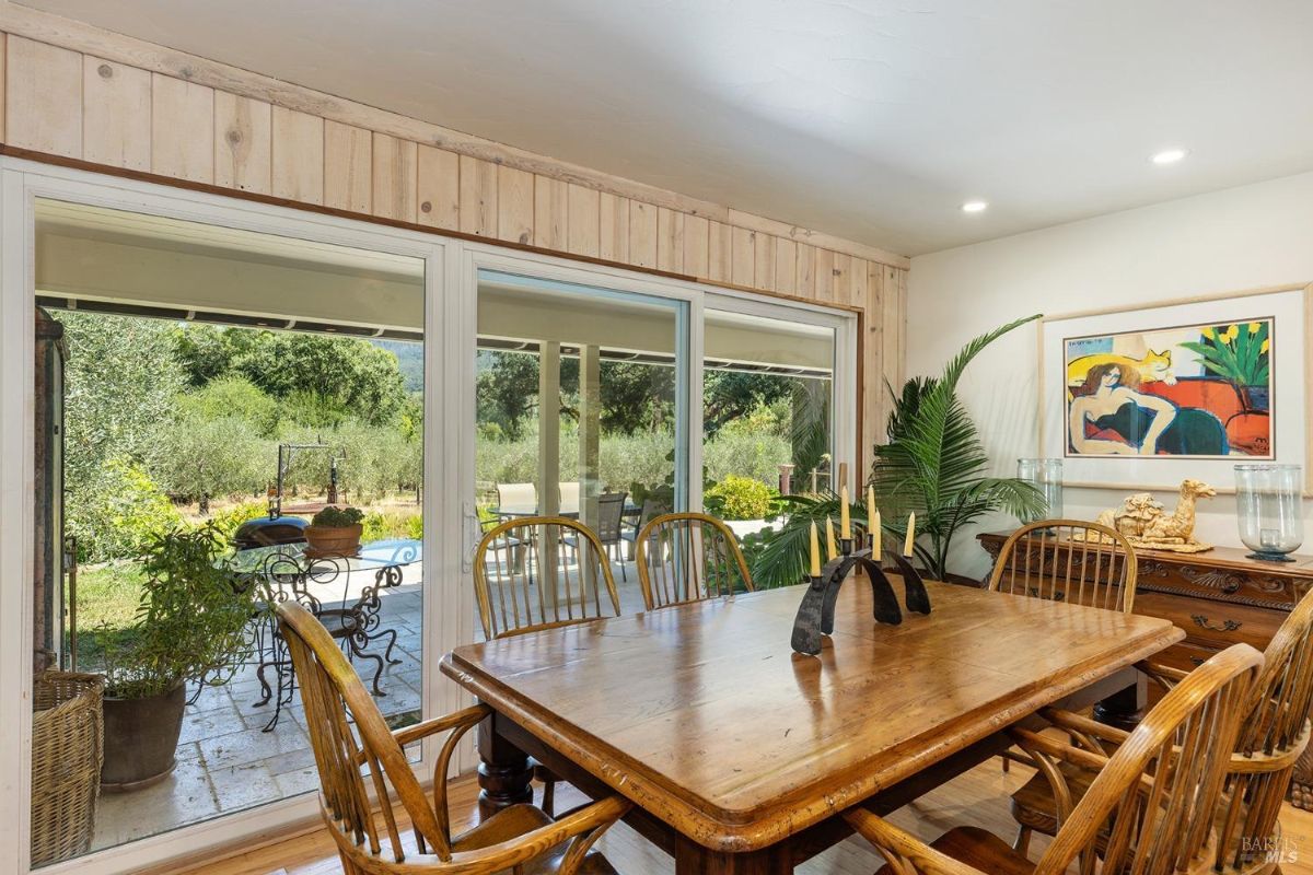 Dining area featuring a wooden table with chairs and a view of an outdoor patio through sliding glass doors.