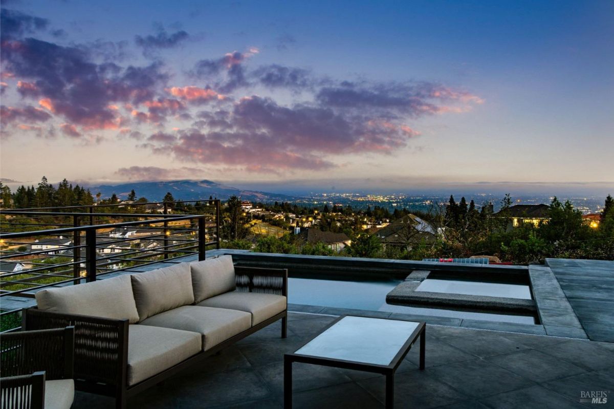 Backyard with a modern pool, patio, and scenic hillside surroundings.